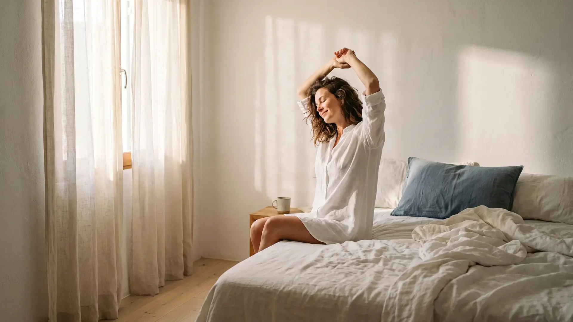 Mujer despertando descansada en un dormitorio luminoso tras dormir en el colchón adecuado